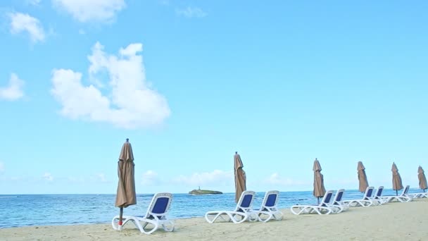 panoraama sininen valtameri ja kultainen hiekka ranta tuolit ja suljetut sateenvarjot
 - Materiaali, video