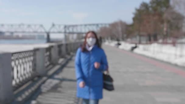 A girl walks in a protective mask on the riverfront. Prevention and protection of health and safety of life. - 映像、動画