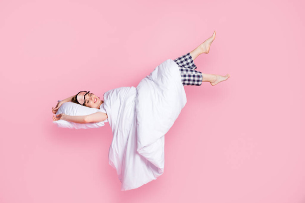 Full length photo of pretty lady enjoy nap lying bed pillow blanket sleep walk raise legs up empty space wear mask white t-shirt pajama pants barefoot isolated pink color background - Fotoğraf, Görsel