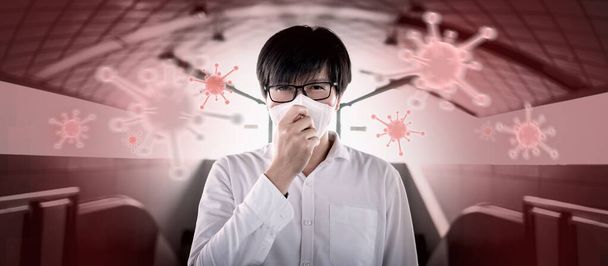 COVID-19 salgını ya da Coronavirüs enfeksiyonu konsepti. Kırmızı arka planda uçan virüs virüsü olan Asyalı bir adam öksürüyor. Solunum damlacıkları yüz maskesi takarak iletim koruması. - Fotoğraf, Görsel