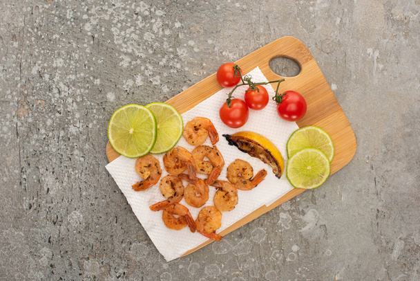 top view of fried shrimps with cherry tomatoes and lime on grey concrete background - Photo, Image