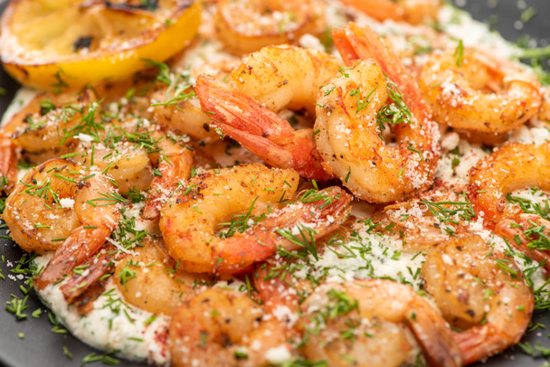 close up view of fried shrimps in sauce with dill and lemon in black plate - Foto, Imagem