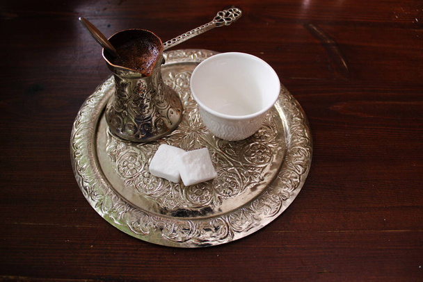 Bosnian coffee. A metallic tray with copper plated cezve dezva filled with traditional foam Bosnian coffee, a clay cup, and sugar cubes served in an ornament Sarajevo set. - Photo, Image