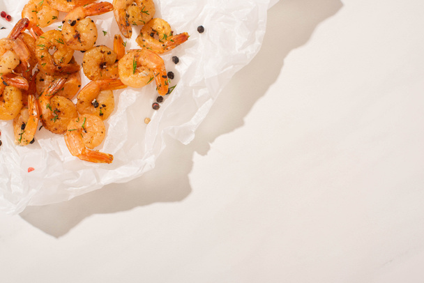 top view of fried shrimps on parchment paper with pepper on white background - Foto, afbeelding