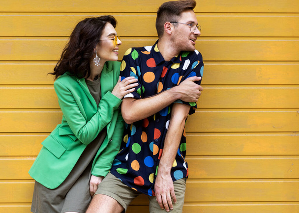 Young fashionable couple on yellow background - Fotó, kép
