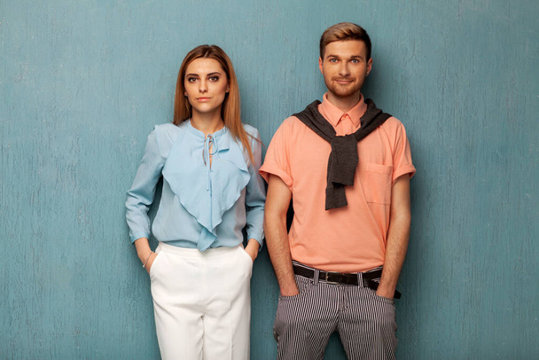 Fashion girl and guy in outlet clothes posing on a blue background - Foto, Bild