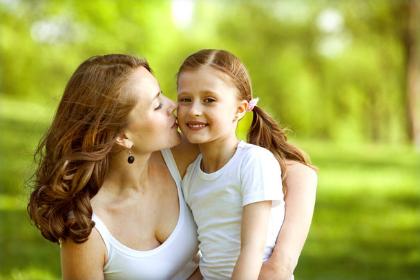 mother and daughter hugging in love playing in the park - Photo, Image