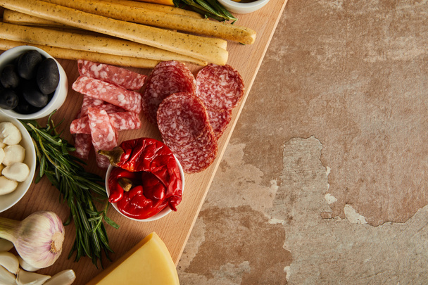 Top view of board with antipasto ingredients on brown background - Foto, Bild