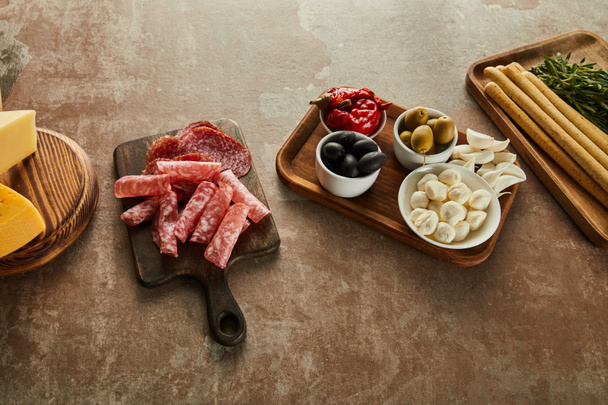 High angle view of antipasto ingredients on boards on brown - Fotografie, Obrázek