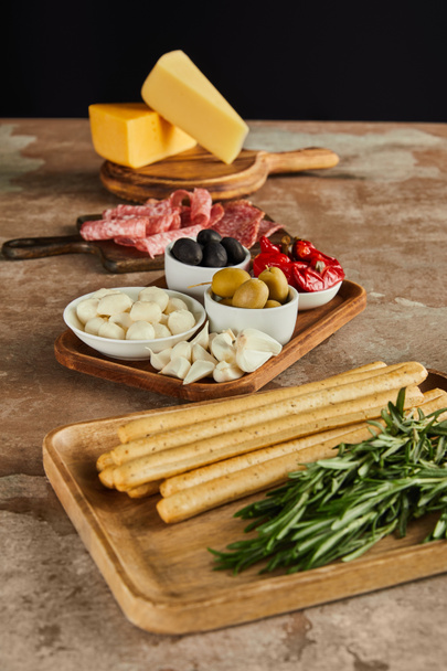 High angle view of antipasto ingredients on boards on brown surface isolated on black - Photo, Image
