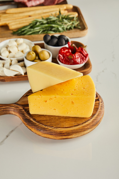 Selective focus of boards with cheese and antipasto ingredients on white - 写真・画像