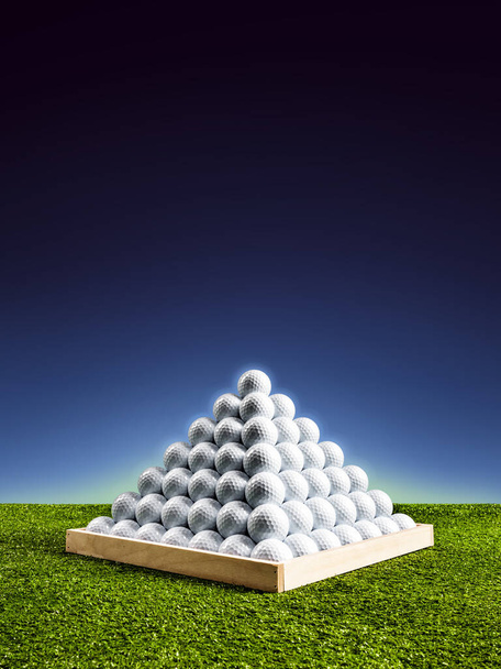 Pirámide de pelotas de golf en un campo de prácticas con brillo de luz azul, imagen vertical
 - Foto, Imagen