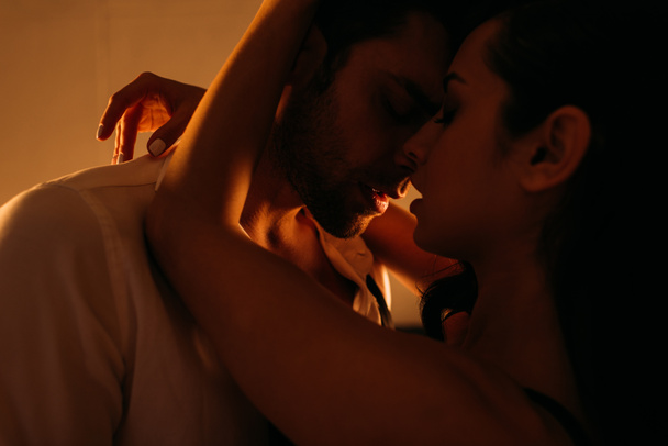 Femme passionnée embrassant homme d'affaires avec les yeux fermés dans la chambre
 - Photo, image
