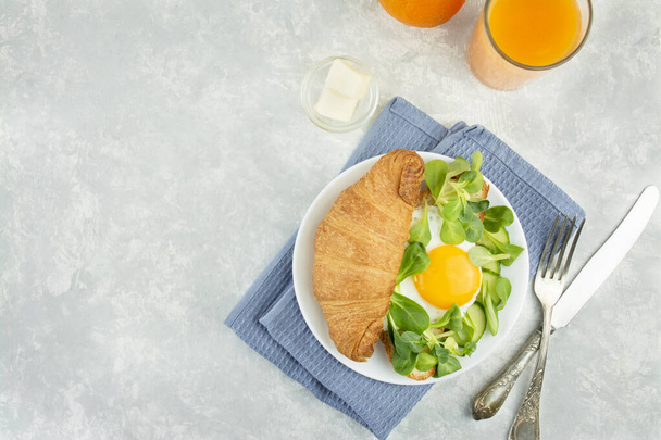 Desayuno europeo con cruasanes frescos, huevos fritos, hierbas y zumo de naranja. Desayuno en una mesa de luz, vista superior. Fondo alimentario
 - Foto, Imagen