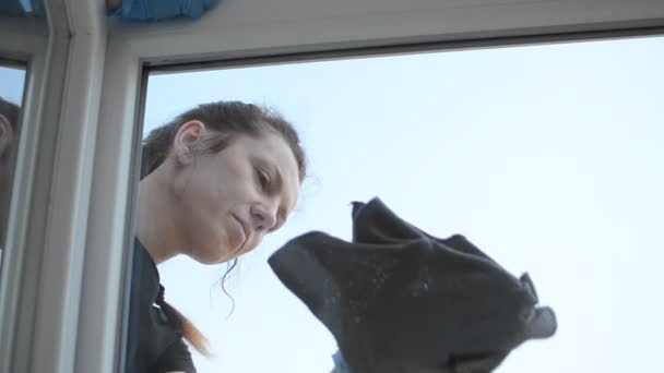 Young woman washes a window with a rag - Séquence, vidéo