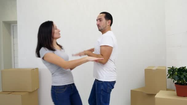 Cariñosa pareja familiar joven divirtiéndose y bailando entre cajas de cartón en su nuevo y acogedor apartamento
. - Imágenes, Vídeo