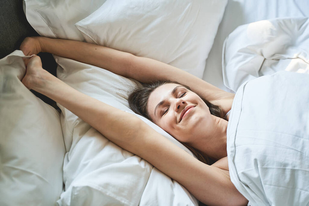 Girl with her eyes shut lying in a bedroom - Фото, зображення