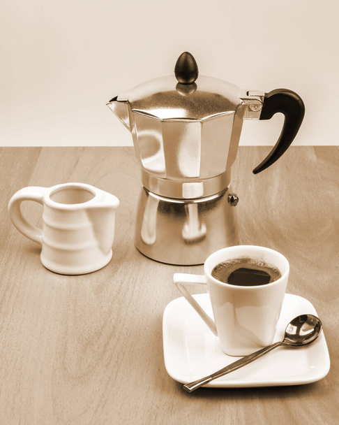 Table setting for coffee. Geyser coffee maker, milk jug and cup and saucer - Photo, Image