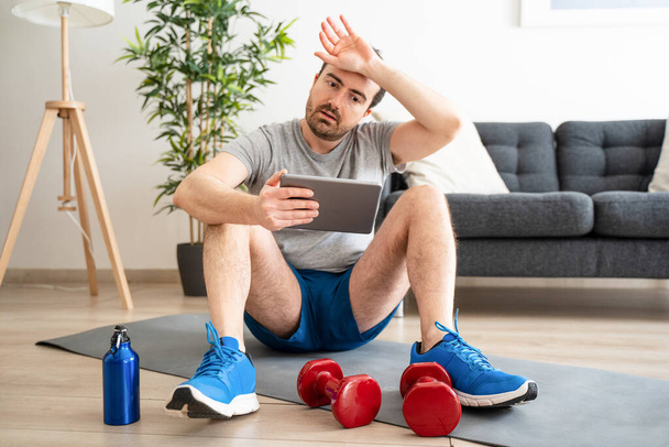 Man doing home work out while watching tutorial on digital tablet - Foto, Bild