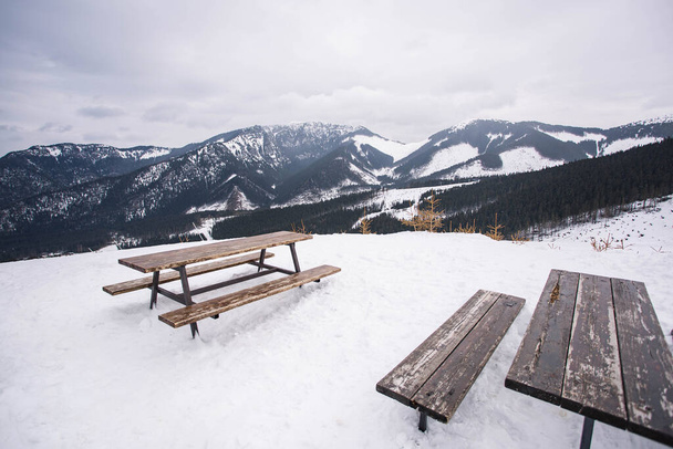Jasna ski resort. Amazing view from the wooden table and benches to  mountains tops in the foggy sky . Low Tatras mountains, Slovakia. - Photo, Image