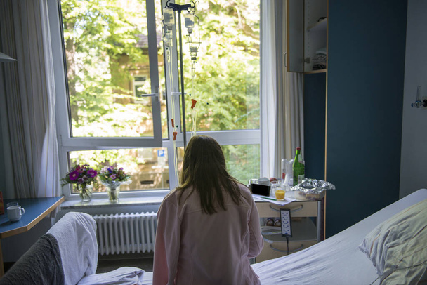 COVID-19. Giovane donna che sta male in ospedale con un catetere in mano, epidemia di coronavirus. Covid paziente guardando smartphon
 - Foto, immagini
