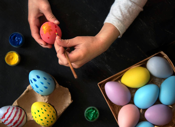 Çocuk elleri Paskalya yumurtalarını farklı renk ve kalıplarla boyar. - Fotoğraf, Görsel