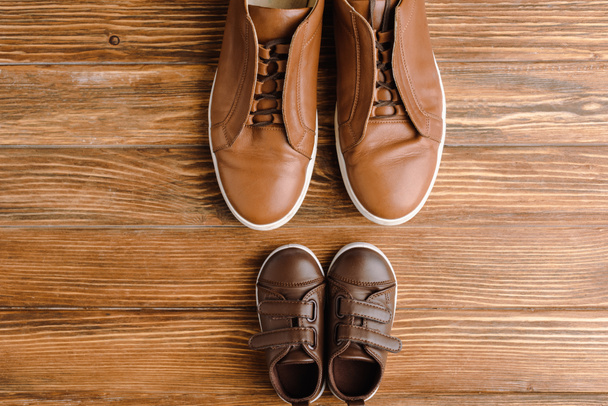 Chcete-li zobrazit pánské a dětské hnědé ležérní boty na texturovaném dřevěném pozadí, otců den koncept - Fotografie, Obrázek