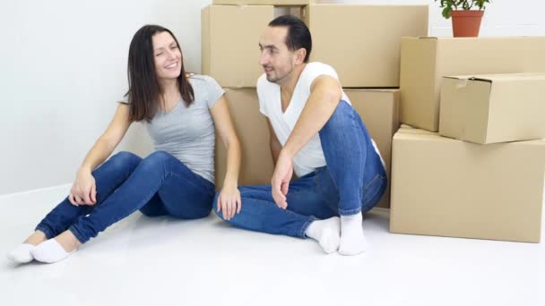 Junge Frau und Mann trugen schwere große Kisten in neue Wohnung und ruhten dann müde, aber zufrieden zusammen. - Filmmaterial, Video