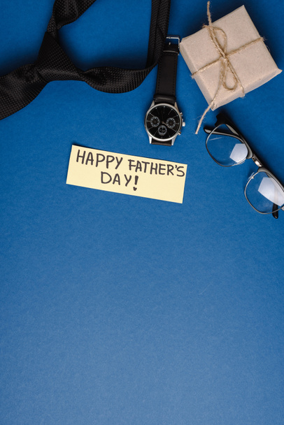 Top view of gift box, greeting card with lettering happy fathers day, mens accessories on blue background - Фото, зображення