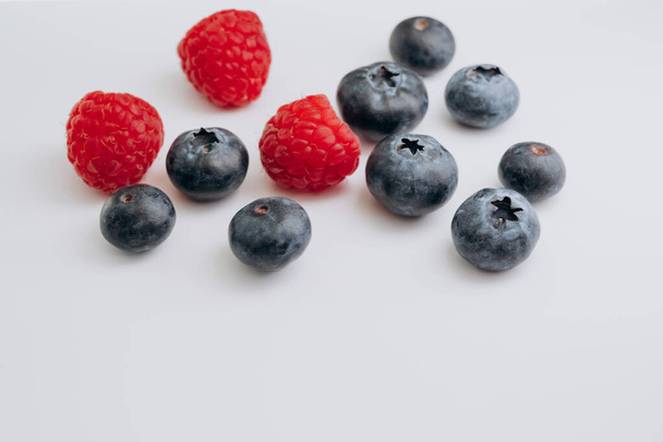 juicy fresh berries blueberries and raspberries are on the white table - Fotografie, Obrázek