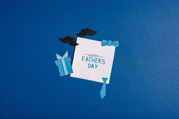 top view of greeting card with lettering happy fathers day and paper craft decorating elements on blue background - Φωτογραφία, εικόνα