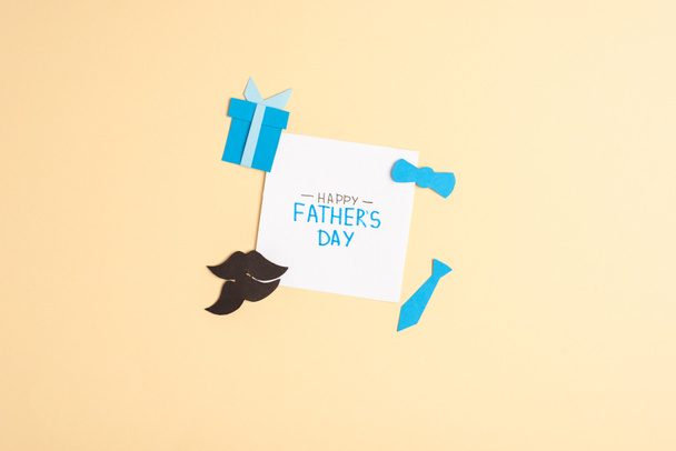 Vue du dessus de la carte de vœux avec lettrage fête des pères heureux et éléments décoratifs en papier sur fond beige
 - Photo, image