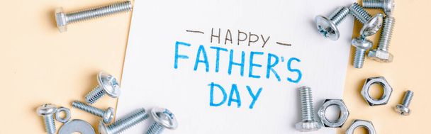 panoramic shot of nuts and bolts and greeting card with lettering happy fathers day on beige background  - Foto, Imagen