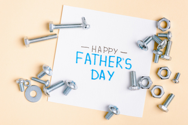 top view of metal nuts and bolts and greeting card with lettering happy fathers day on beige background  - Foto, immagini