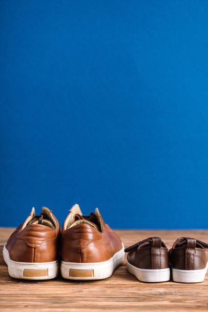 Мужчины и дети случайные бежевые туфли на деревянной поверхности изолированы на синий, День отца концепции
 - Фото, изображение