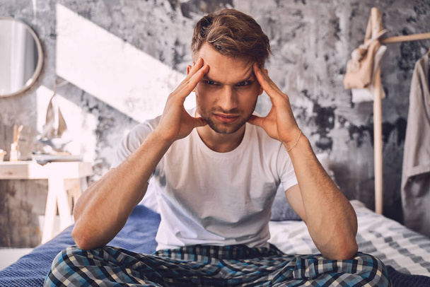 Serious young male touching his head during thinking - Photo, Image