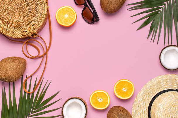 Summer fashion flat lay. Round trendy rattan bag straw hat sunglasses tropical palm leaves coconut orange on pink background. Top view copy space Trendy bamboo bag Creative background vacation concept. - Photo, Image
