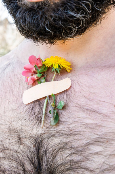 Malé kytice jarní květiny přilepené na tělo dospělý vousatý muž. Koncept jarního času po pandemii. - Fotografie, Obrázek