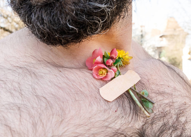 Pequenas flores de primavera de buquê coladas no corpo homem barbudo adulto. O conceito primavera após a pandemia
. - Foto, Imagem
