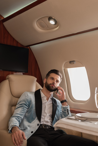 confiant, élégant homme parlant sur smartphone tout en voyageant en jet privé
 - Photo, image
