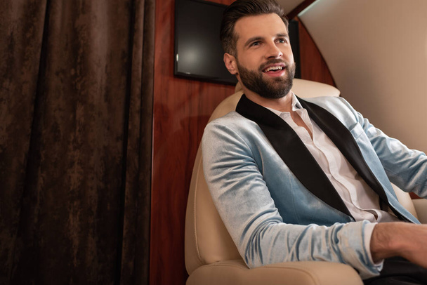 handsome, elegant man smiling while traveling in private jet - Foto, Bild