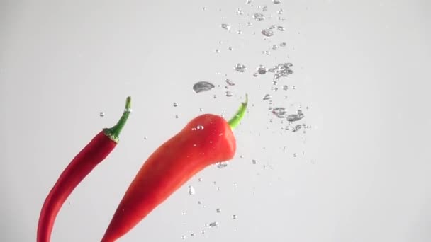 Hot peppers falling into the water. Slow motion - Imágenes, Vídeo