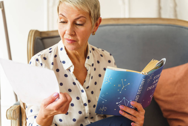 Pleasant blonde woman holding an astrology book - Foto, imagen