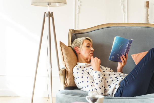 Focused blonde woman reading an astrology book - Fotoğraf, Görsel