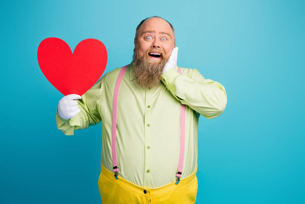 Portrait of his he nice funny funky dreamy cheerful cheery delighted man holding in hand big large heart enjoying 14 February isolated over bright vivid shine vibrant blue color background - Photo, Image