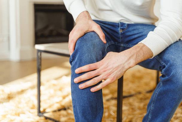 mężczyzna dotykając jego zapalenie kolana obiema rękami - Zdjęcie, obraz