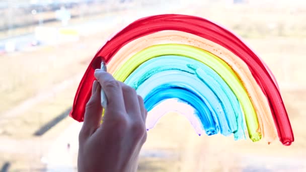4k. Girl painting rainbow on window during Covid-19 quarantine at home. Stay at home social media campaign for coronavirus prevention, lets all be well, hope. Catch the rainbow. - Séquence, vidéo