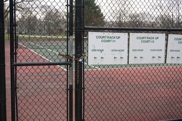 Tennis courts at a suburban Chicago park are padlocked to enforce the governor's shelter in place mandate and to keep residents social distancing during the COVID-19 pandemic. - Photo, Image