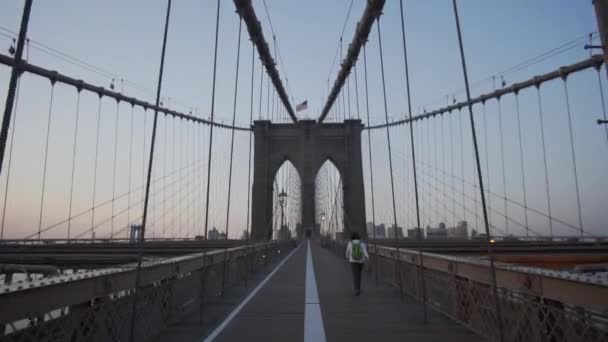 Brooklyn Bridge a nő sétál kora reggel napkeltekor gyönyörű napsütésben nyáron  - Felvétel, videó