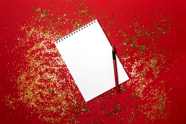 Notepad for notes on a festive red background with gold particles. Holiday design. - Photo, image